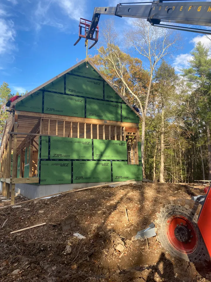 A green house being built with trees in the background.